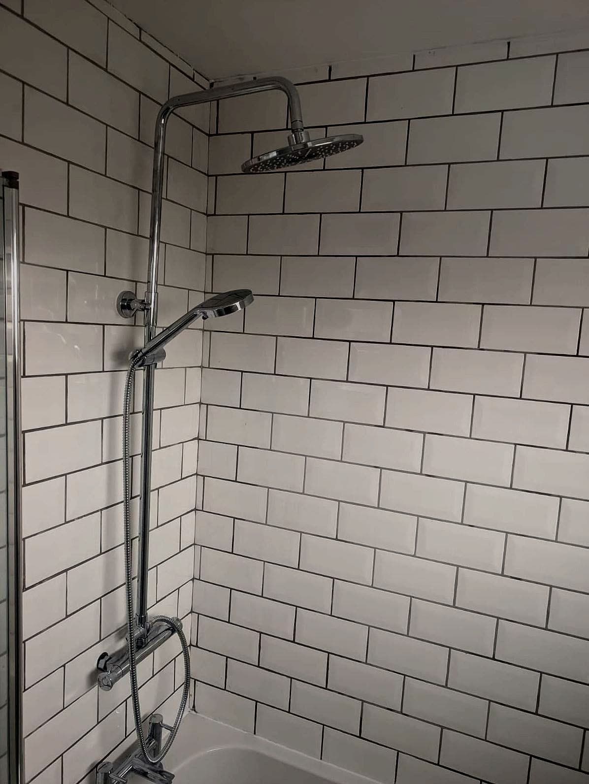 Shower over the bath, white metro tiles up to the ceiling