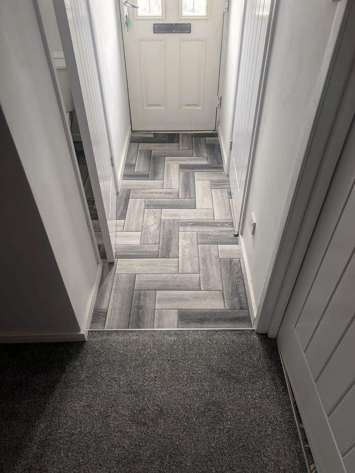 Hallway with herringbone-effect flooring running to the front door