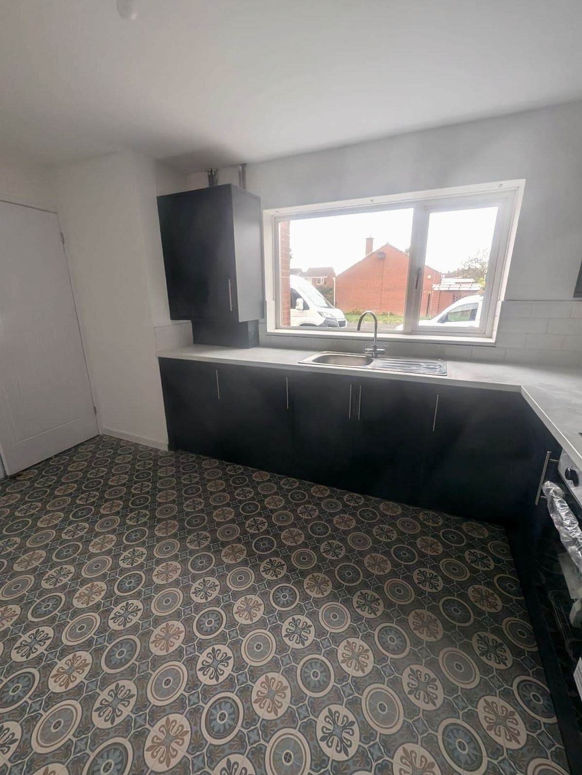Kitchen finished: dark units, a patterned floor and the window over the sink