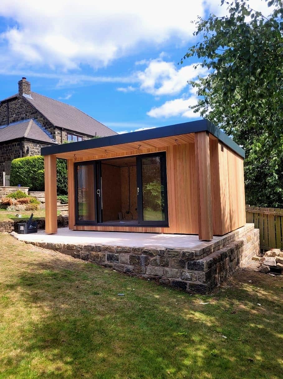 Cedar-clad garden room on a stone base with full glass doors