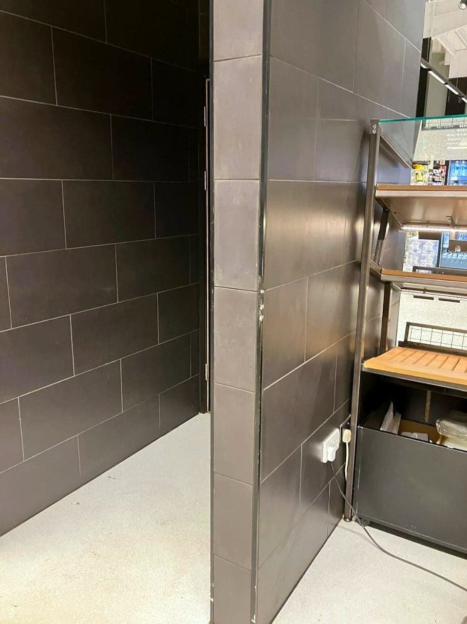 Dark rectangular wall tiles beside a shelving unit in a store