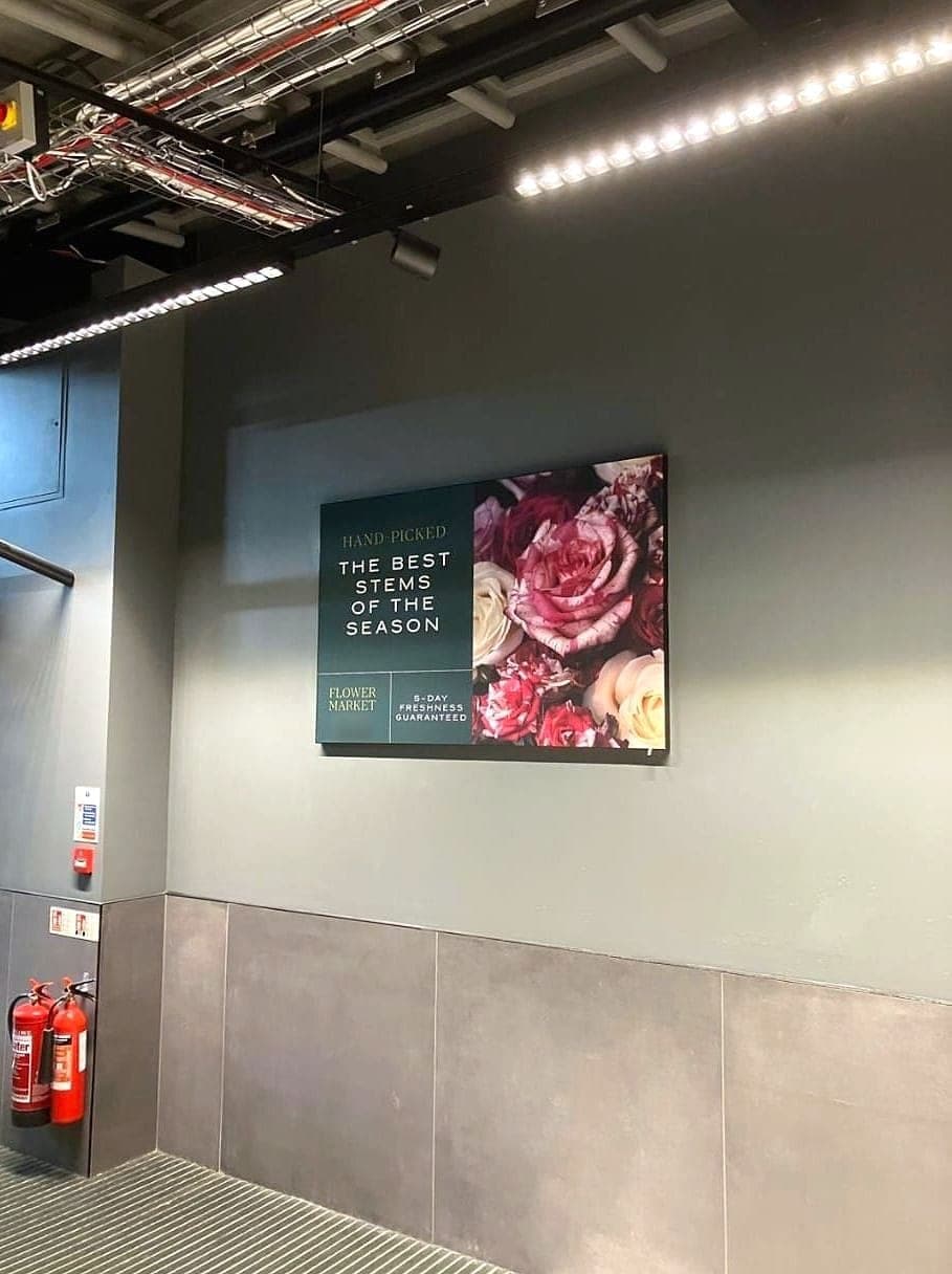 Store wall painted grey above large grey wall tiles, with a sign