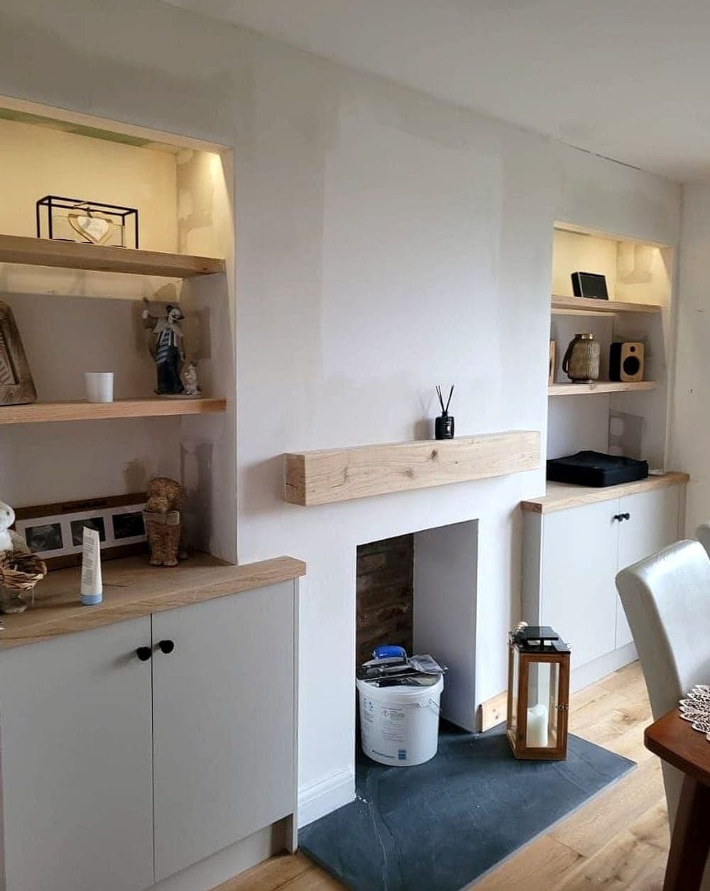The same alcoves finished, shelves lit and dressed either side of an oak mantel