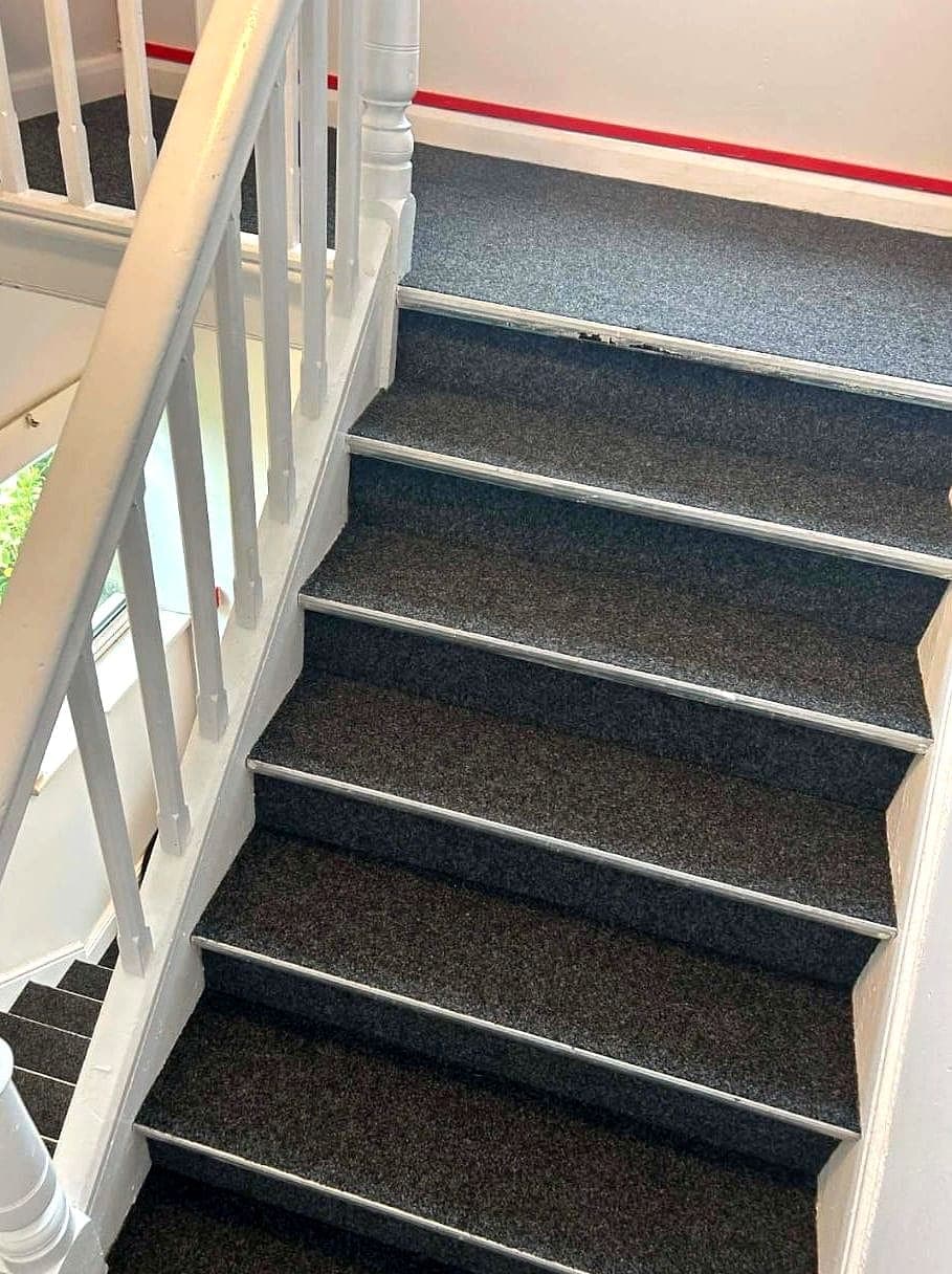 New charcoal carpet up the stairs beside white spindles